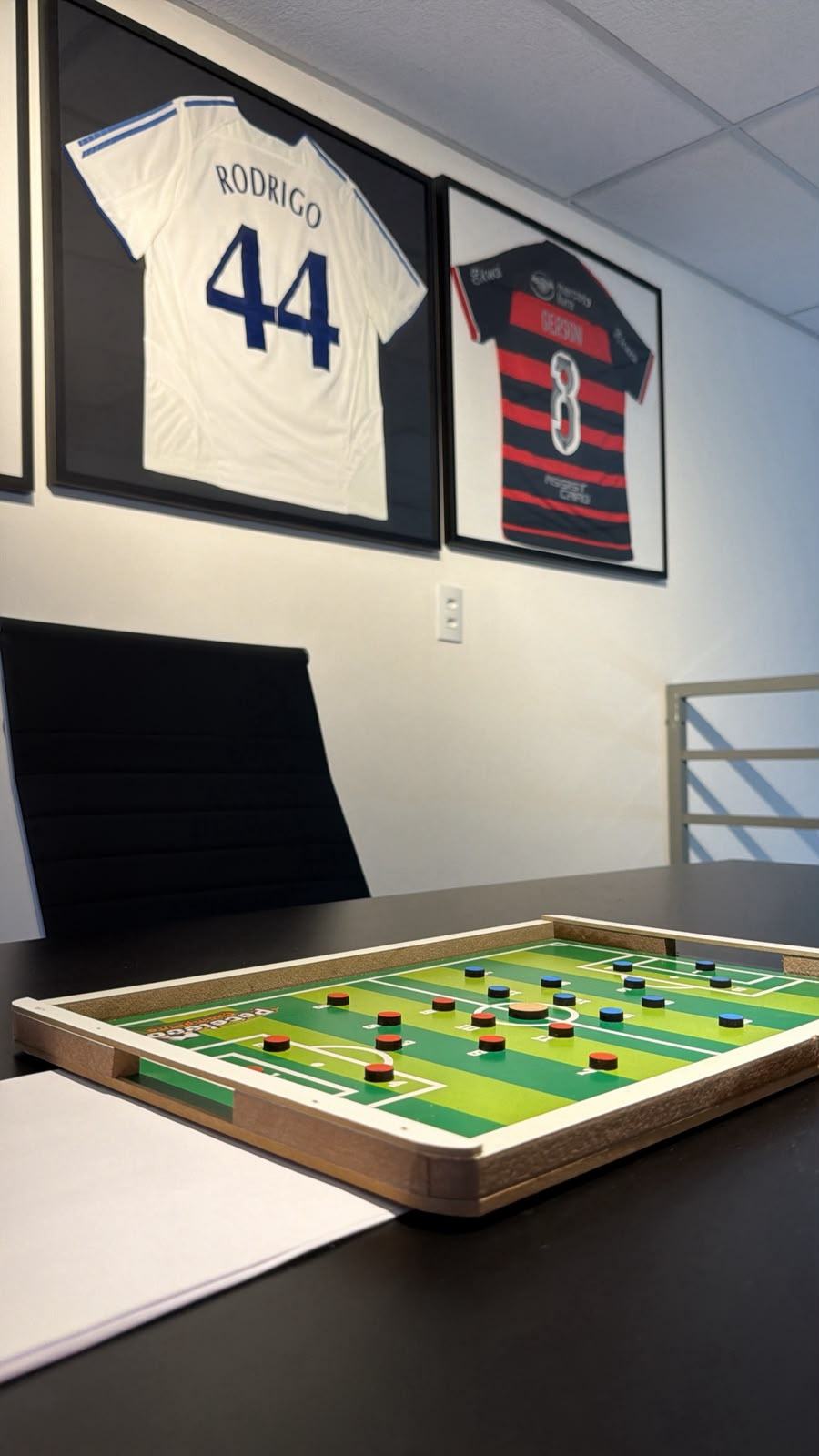 Sala da Four Crédito Sports com camisas de futebol emolduradas e mesa de estratégia